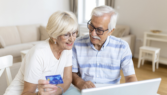Senior Couple Using Laptop To Shop Online. Elderly couple paying bills online on laptop.